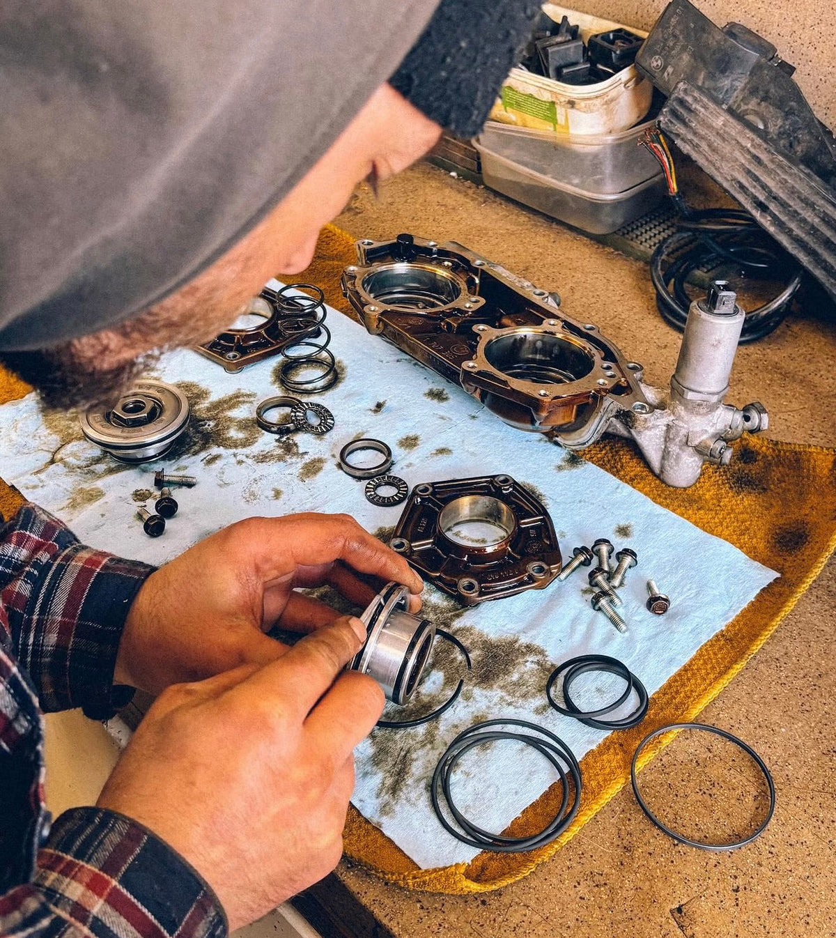 A mechanic working on rebuilding a BMW E46 VANOS on a work bench.